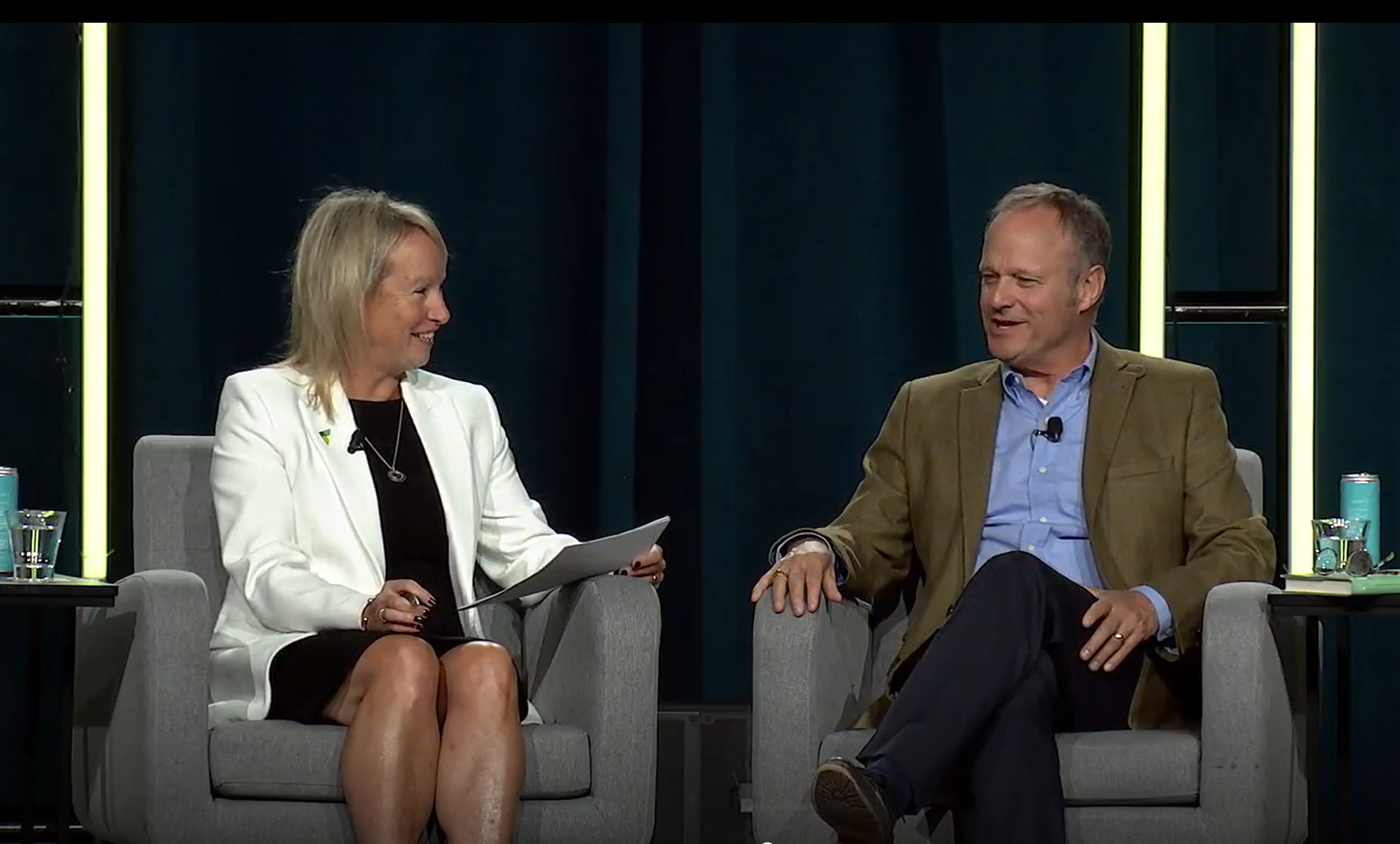 Photo captured from an audience member perspective of Eileen McAuliffe (left) and Andrew J. Hoffman (right) both seated in light gray chairs speaking during a keynote session at AACSB's October 2025 Deans Conference in Toronto, Canada